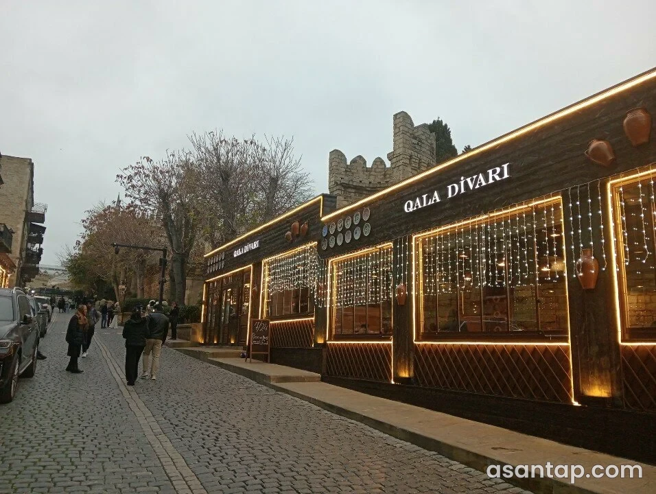 Qala Divarı Restoranının qala divarı yanındakı işıqlı fasadı və girişi