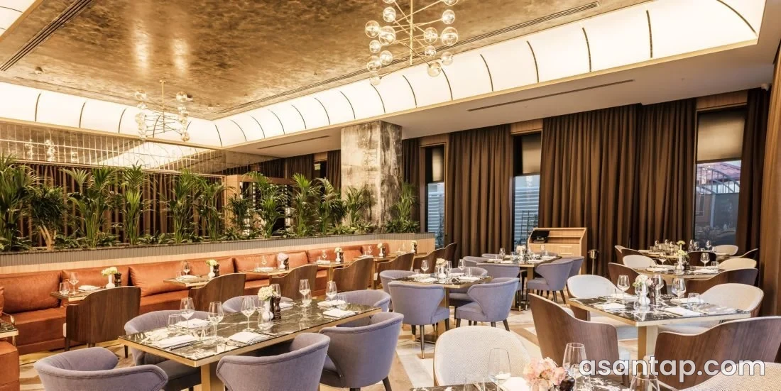 Khamsa Restaurant — InterContinental Baku — restoranın rəsmi fotosunda masa və oturacaqlarla yemək salonu