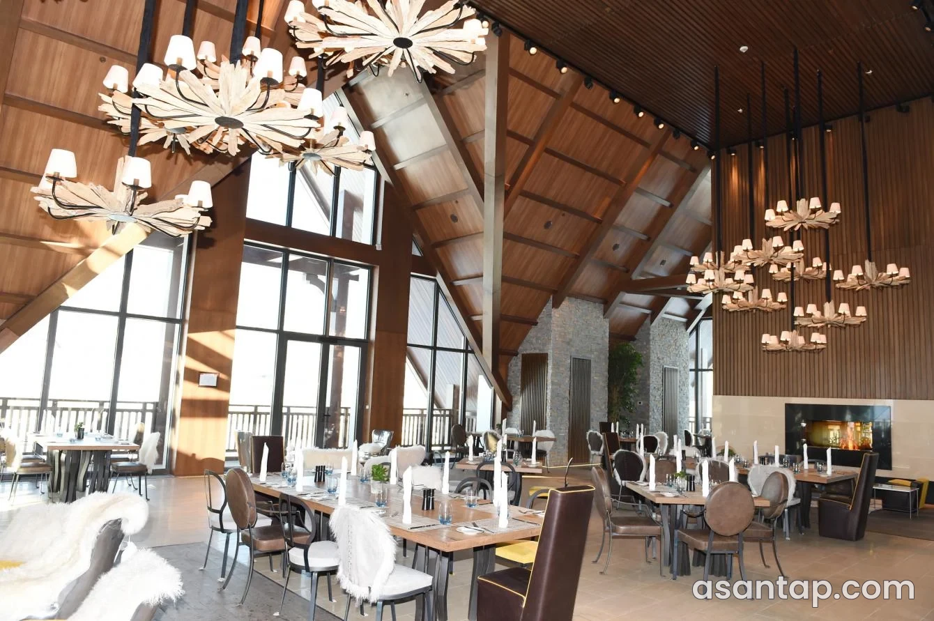 Aspen Grill restoranının taxta tavanlı, daş sütunlu və çilçıraqlı zalı